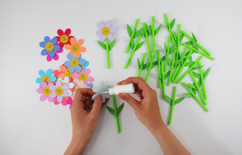 Gluing head of number flower onto straw stem